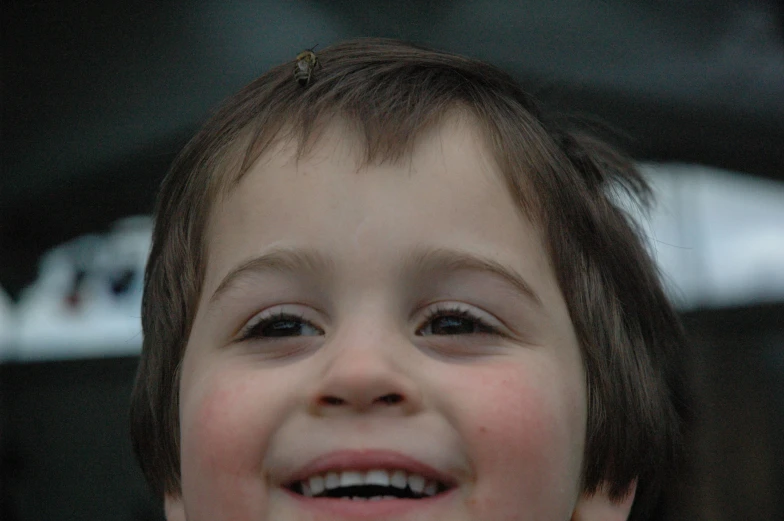 a child smiling for the camera near a black car