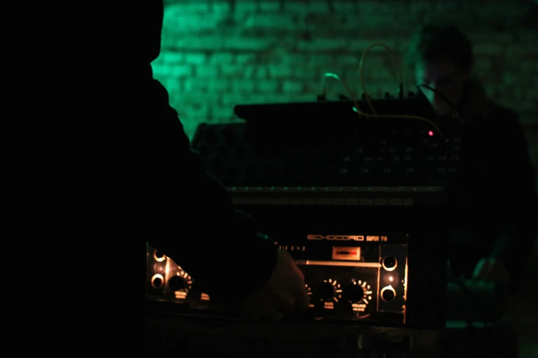 dark silhouettes of people standing around the controls of some instruments