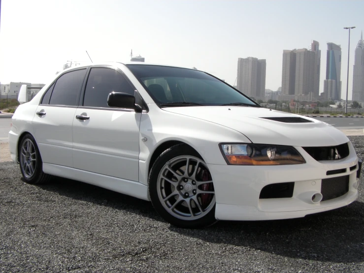 the white car is parked in front of some tall buildings