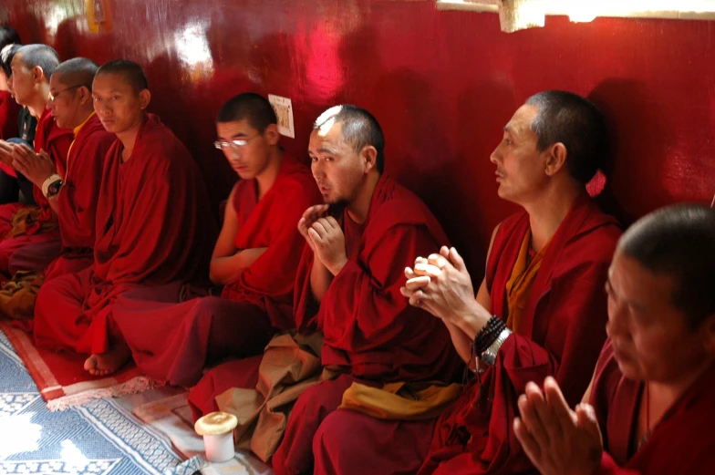 a group of monks sitting around each other with their hands together