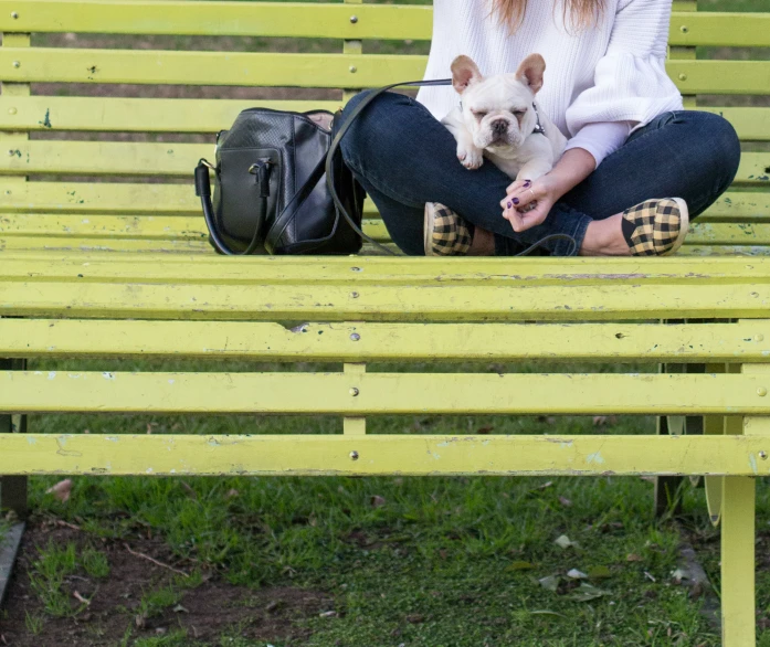 a woman with long hair sitting on a bench next to her dog