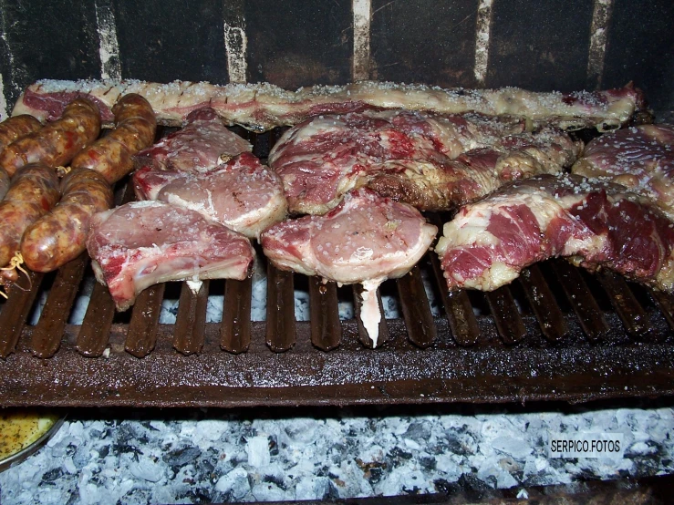 some meat are cooking on a grill with potatoes