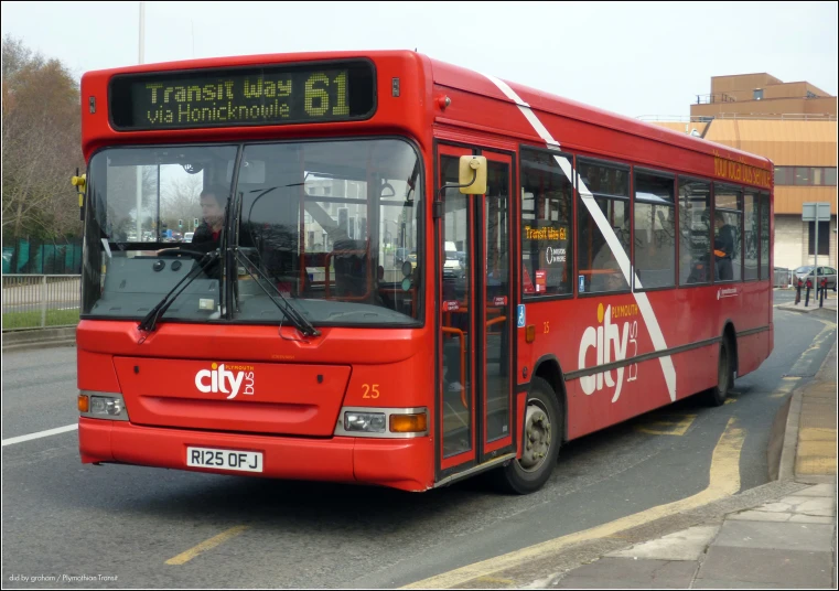 the red city bus is stopped in the road