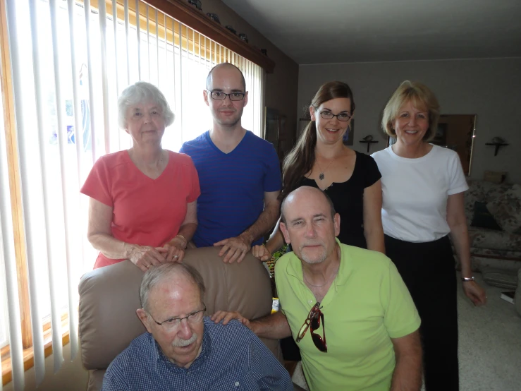 five people posing for the camera in front of blinds