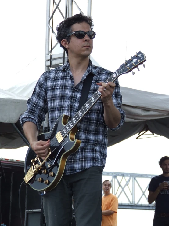 a man in glasses plays an electric guitar