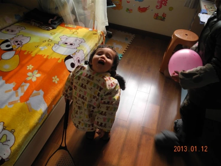 a little girl standing in front of her bed wearing a pyjama and balloon