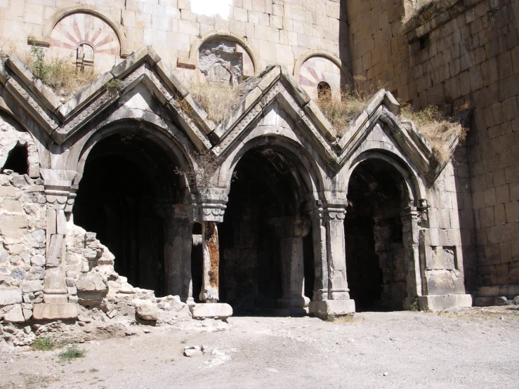 three stone arches and two archways at the entrance of an old building