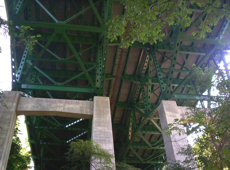 a very tall metal bridge over a stream