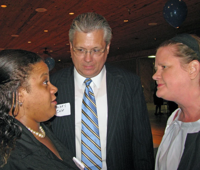 two women and a man in business suits are talking to each other