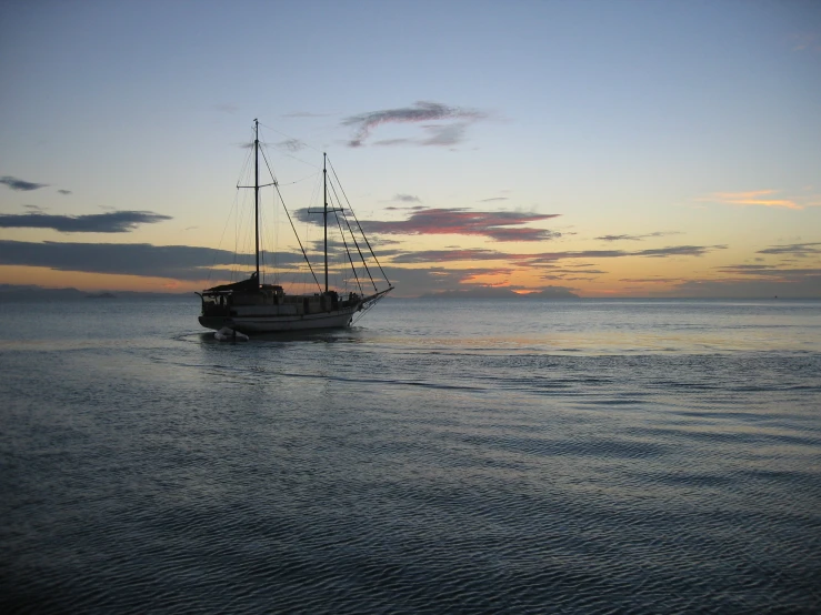 a boat in a bay at sunrise with the sun setting behind it