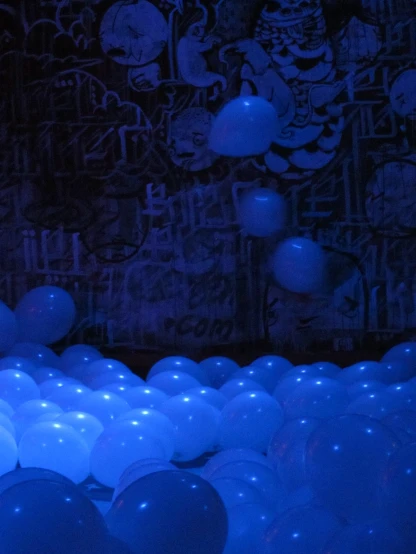 blue lighting shines on the wall of balloons in a room