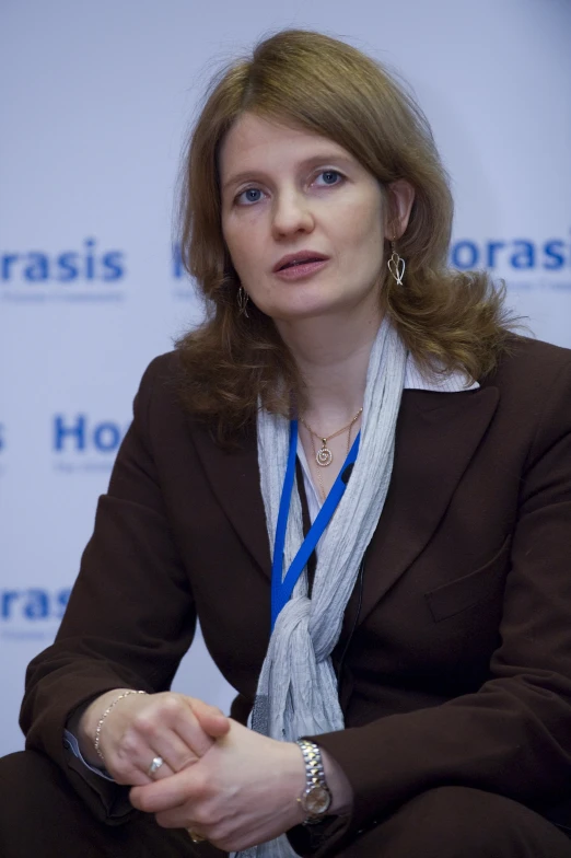 a woman sitting down talking into a microphone