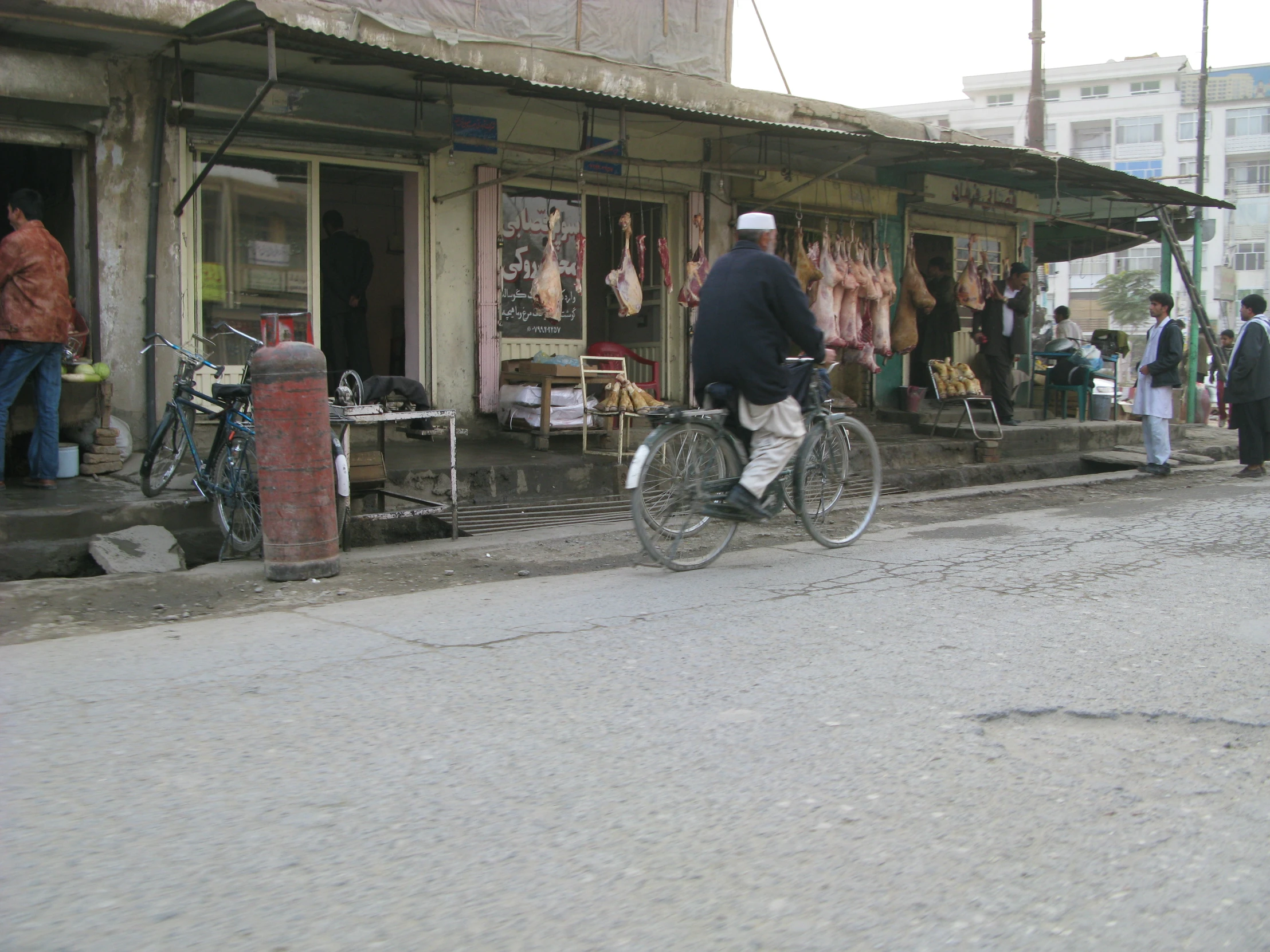 this man is riding his bicycle down the street in front of his shop