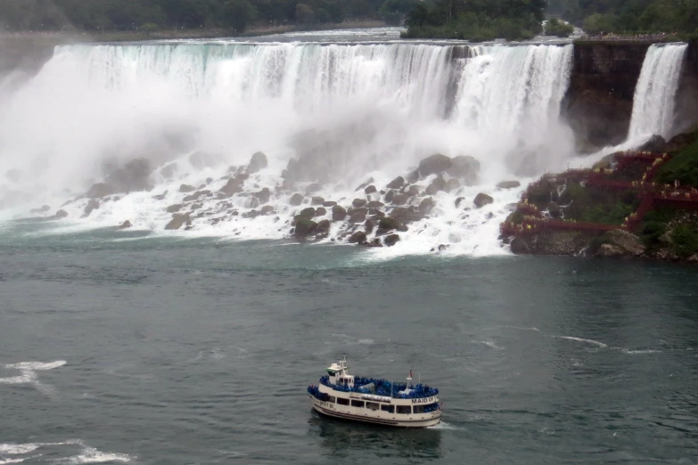 the boat is driving down the river past the waterfall