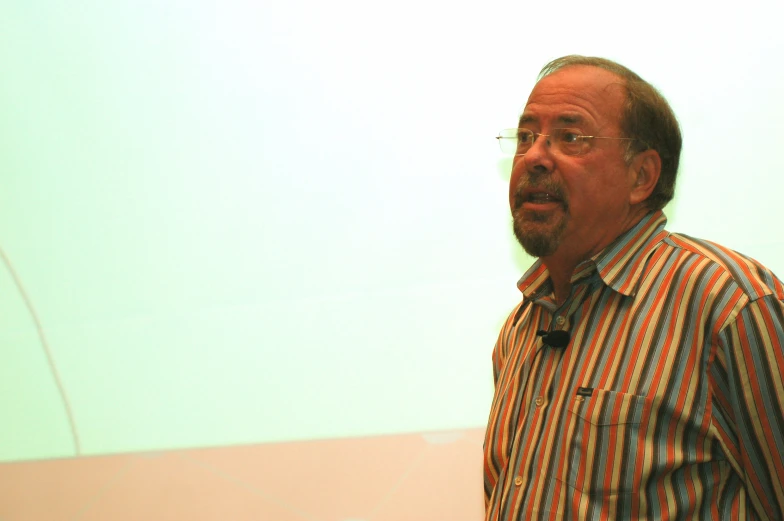 a man is shown standing in front of the projection screen