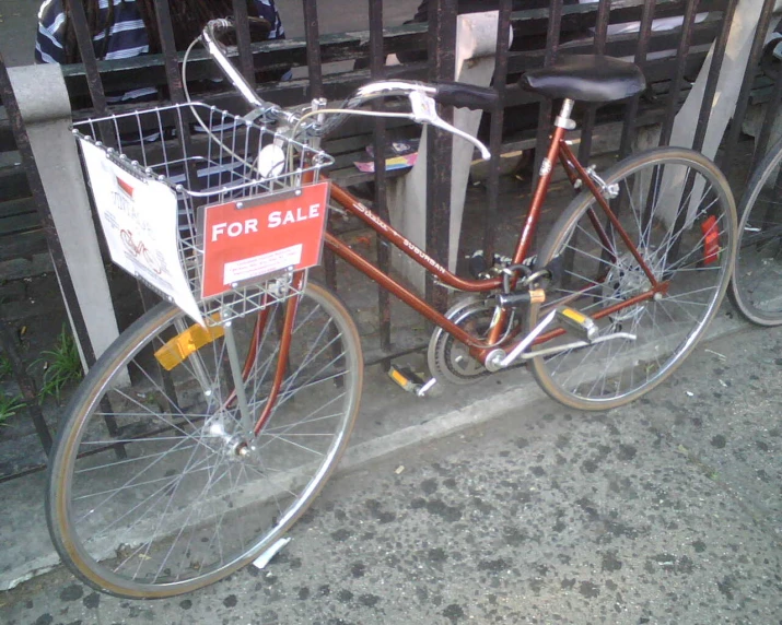 a bicycle  up on the sidewalk by a fence