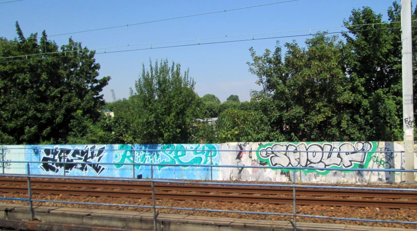 a railroad tracks next to some graffiti on a wall