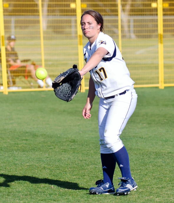 woman pitching a ball wearing a catchers mitt