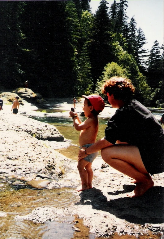 a mother takes her child's picture while the baby is on the beach