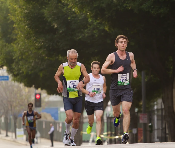 four men are running down the street during a marathon