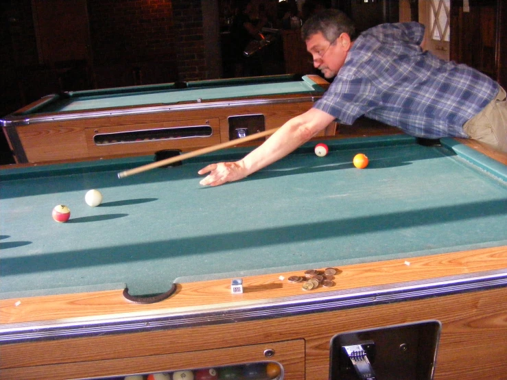 a man is reaching up to reach a pool ball