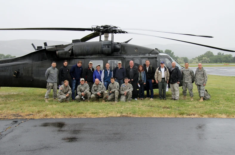 the men are posing for a group po in front of an air force helicopter