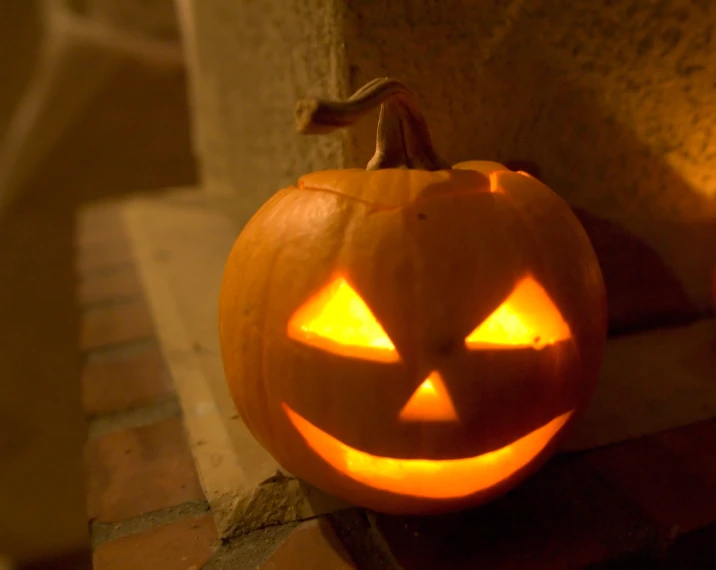 a carved pumpkin on the ground in front of a house