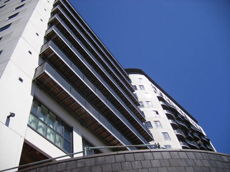 two tall building against a blue sky and a grey brick wall