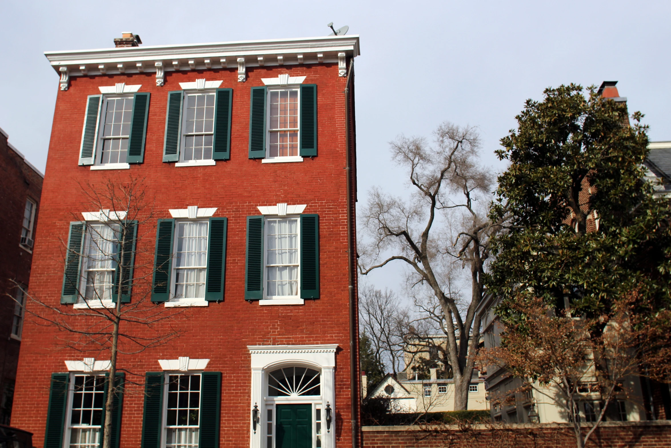 a brick building with green shutters and windows