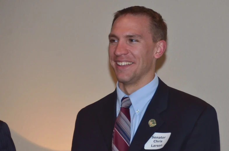 a man smiling with a badge on his lapel