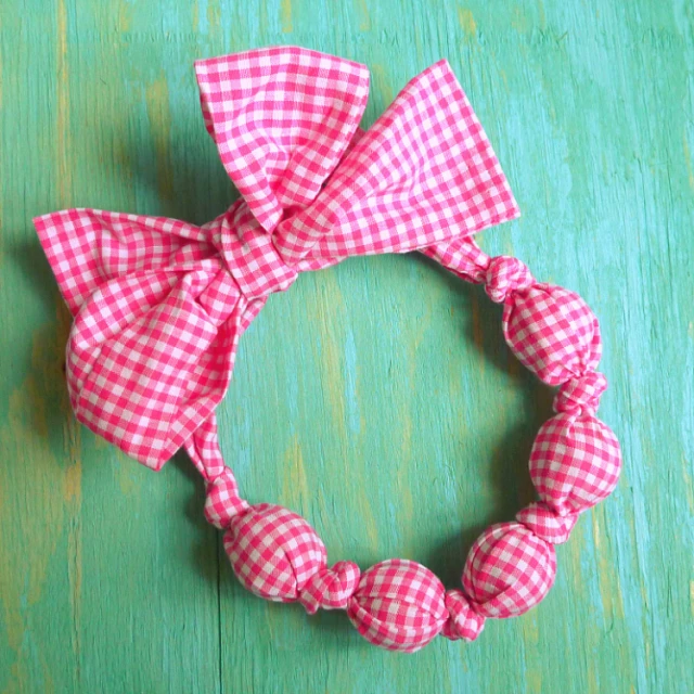 a pink gingham ribbon bow on a wood floor