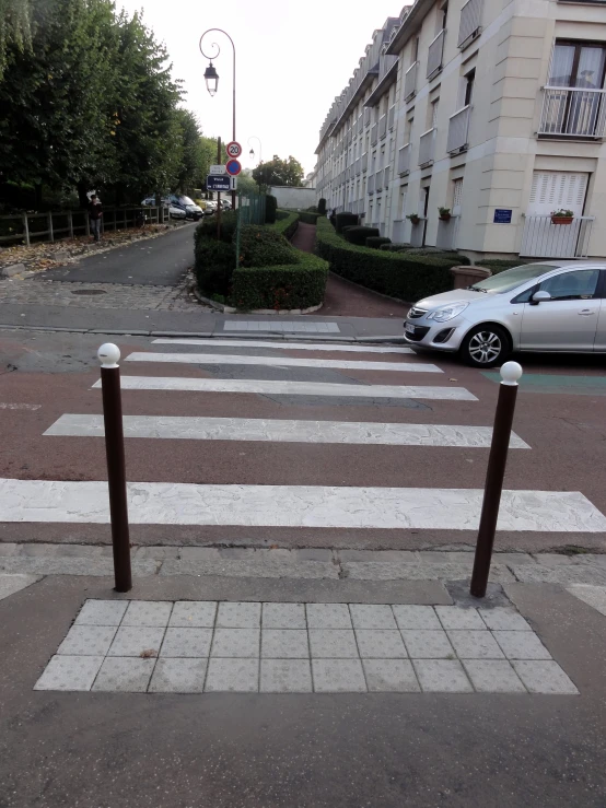 this is a crosswalk and a street with cars parked along the sidewalk