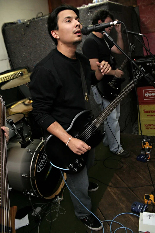 two young men playing guitar and singing on stage