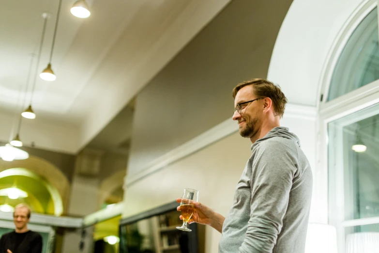 a man with glasses smiling while holding a wine glass