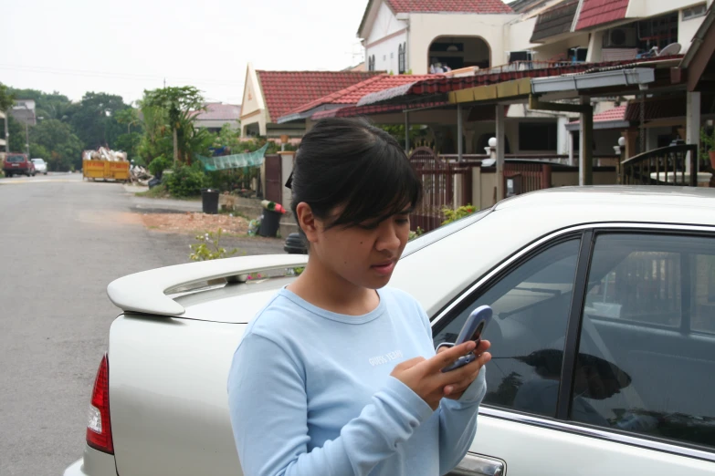 a woman holding a smart phone near a car