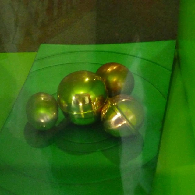 three shiny metal balls are in a green surface