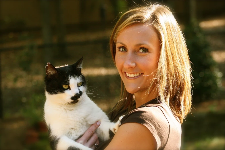 a woman holding a cat in her hands outside