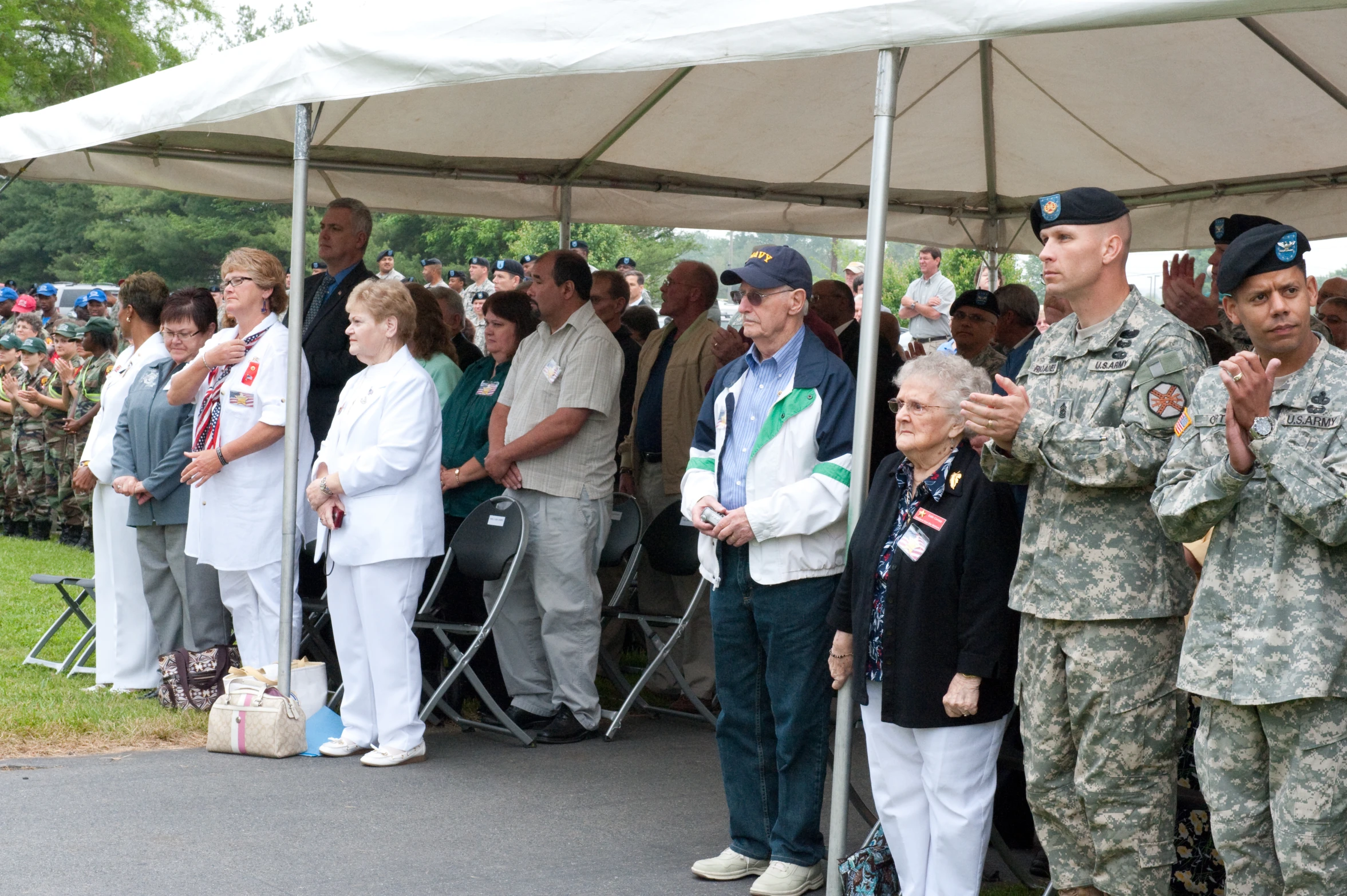 military personnel stand around under a large canopy