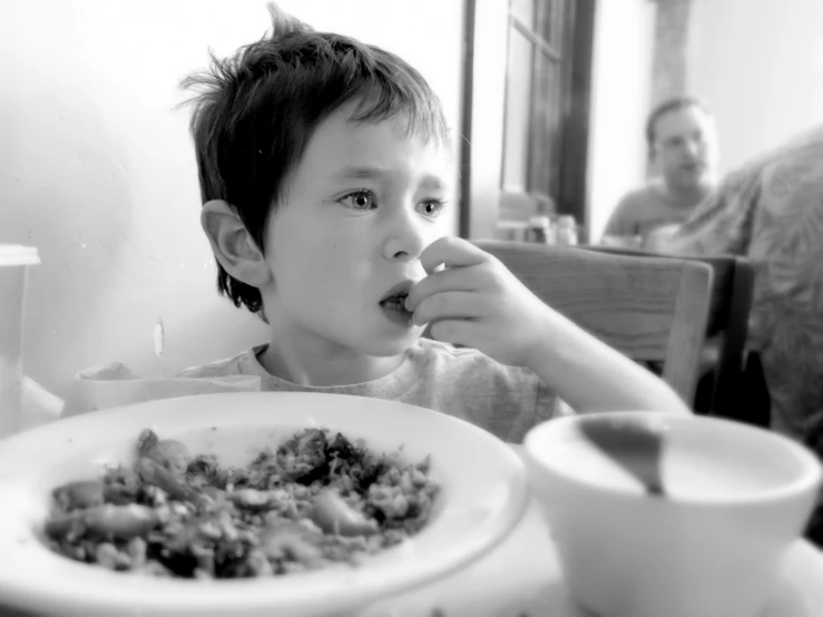 a small boy eats some food at the table