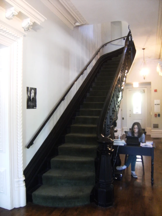 a woman is using her laptop at the top of a stair case