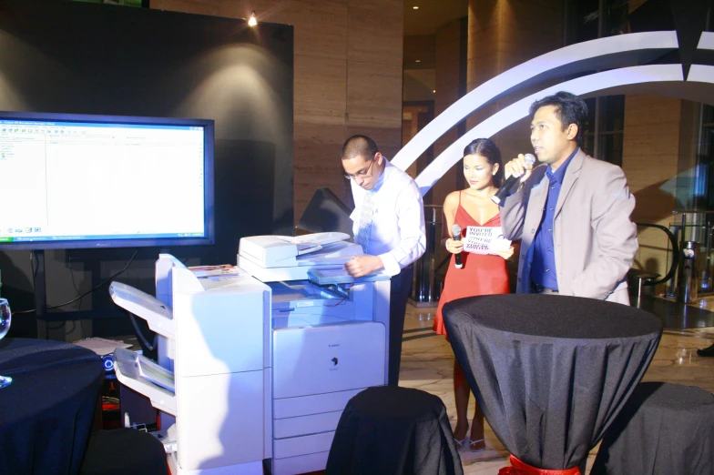 people standing around a large digital printer in an office