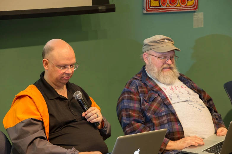 an old man standing next to a young man holding a laptop