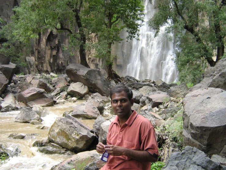 a man standing by a waterfall in the wilderness