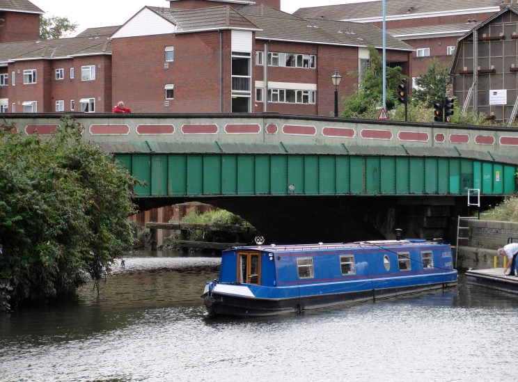 a blue house boat passing under a bridge