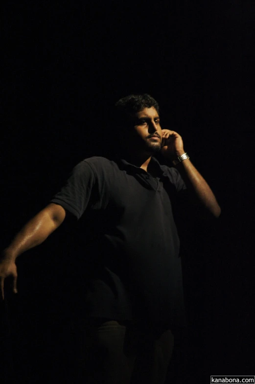 a man standing in the dark with his hand to his face