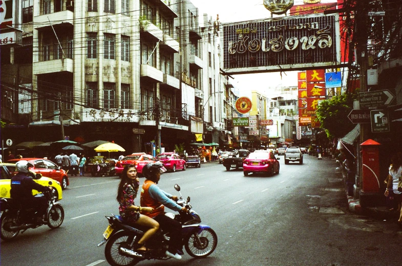 a group of bikers riding down the road with umbrellas