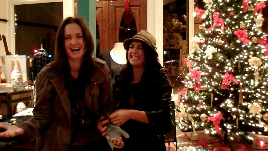 two ladies in front of a christmas tree