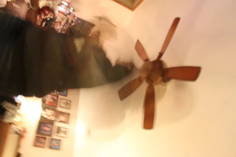 a blurry pograph of a person running in a room with a ceiling fan