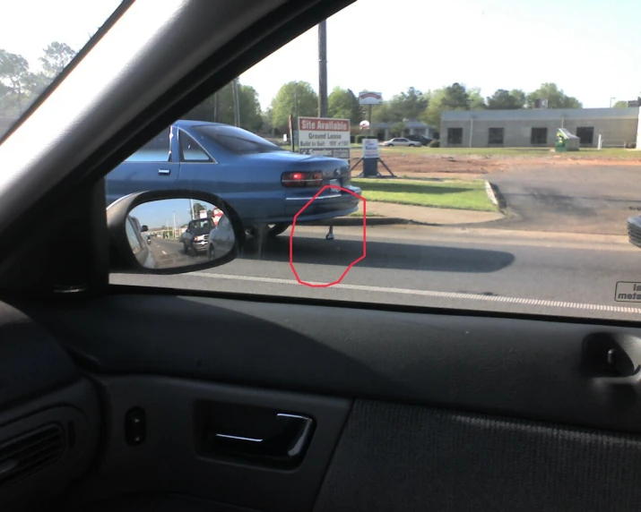 a blue car is seen through a mirror in a parking lot
