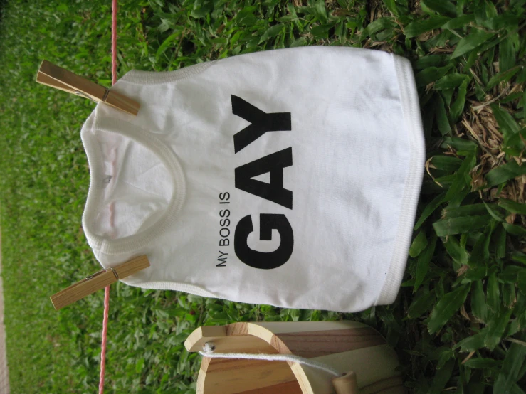 a white shirt that says gay is hanging next to a basket